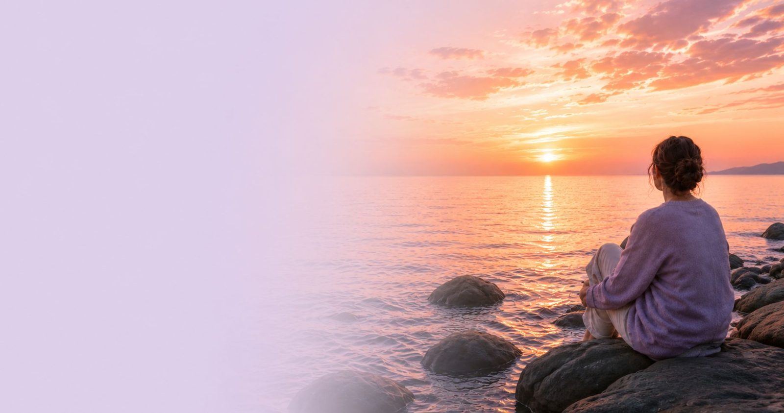 Woman looking out at a calm sunset shoreline
